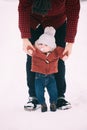 Close up.the father helps his son to take the first steps in snowy winter forest