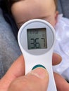Close-up of a father`s hand taking a baby`s temperature with a thermometer