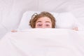 Close up of feet in a bed under white blanket. A young man waking up in bed and stretching his arms. Male men underwear. Royalty Free Stock Photo