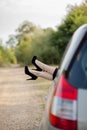 Close-up of feet with black shoes on high heels of attractive girl. She is putting her legs through the window of modern transport Royalty Free Stock Photo