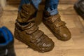 Close-up of feet in boy& x27;s muddy boots, standing guiltily in hallway