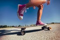 Feet of a girl in red sneakers riding on the skateboard on the road