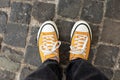 Close Up Feet of girl in stylish casual shoes. Female in yellow sneaker being walking down the street.