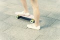 Close up of feet of a girl in white sneakers and pink penny skate board