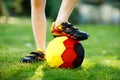 Close-up of feet of kid boy with football and soccer shoes in German national colors - black, gold and red. World or Royalty Free Stock Photo