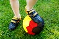 Close-up of feet of kid boy with football and soccer shoes in German national colors - black, gold and red. World or Royalty Free Stock Photo