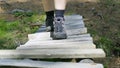 Close-up of a man`s feet walking on a flimsy wooden bridge