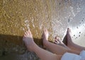 feet of a mother and child stand on the sand by the sea shore Royalty Free Stock Photo