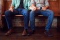 Close Up On Feet Of Same Sex Male Couple Holding Hands Sitting On Bench Together