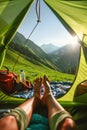 Close up of feet in a tent, a woman lying inside a green popup camping tent with a view of a grassy mountain landscape Royalty Free Stock Photo
