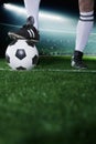 Close up of feet on top of soccer ball, night time in the stadium Royalty Free Stock Photo