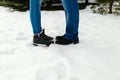 Close-up feet of a young couple in warm winter shoes standing on the snow. The legs of a man and a woman in winter boots stand on Royalty Free Stock Photo