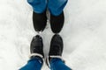 Close-up feet of a young couple in warm winter shoes standing on the snow. The legs of a man and a woman in winter boots stand on Royalty Free Stock Photo