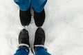 Close-up feet of a young couple in warm winter shoes standing on the snow. The legs of a man and a woman in winter boots stand on Royalty Free Stock Photo