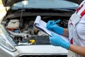 close-up of a female auto mechanic checking a car engine.