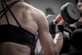 Close up on a female bodybuilder deltoid and trapeze, female bodybuilder doing exercises with dumbbell