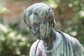 Close up of a female bronze statue of a woman with short hair with cross and cardigan in a park, Germany