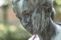 Close up of a female bronze statue of a woman with short hair with cross and cardigan in a park, Germany