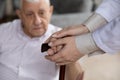 Close up female caregiver holding mature patient hands on cane