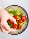 Close up of female chef hand putting Feta cheese cubes on greek vegan tomato salad with olives and lettuce leaves. The concept of Royalty Free Stock Photo