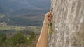 CLOSE UP: Female climber quickdraws a carabiner into a bolt on the rocky cliff
