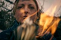 Close-up of a female dirty face through the fire. Homeless by the fire Royalty Free Stock Photo