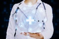 Close up of female doctor hand holding creative glowing blue medical hologram with cross and globe on blurry background. Science,