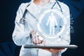 Close up of female doctor hand pointing at tablet with round medical interface with human body outline and healthcare icons on Royalty Free Stock Photo