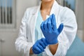 Close up of a female doctor putting a blue latex gloves on a clinic background.