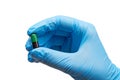 Close up of female doctor's hand in blue sterilized surgical glove holding green and black capsule