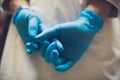 Close up of female doctor`s hands putting on blue sterilized surgical gloves in the office. Royalty Free Stock Photo