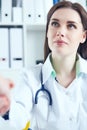 Close up of female doctor shaking hands with her patient. Medicine and trust concept