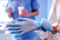 Close up of female doctor's hands putting on blue sterilized surgical gloves in the medical clinic. Royalty Free Stock Photo