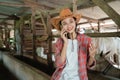 close up of female farmer standing wearing cowboy hat make a calling using smartphone Royalty Free Stock Photo