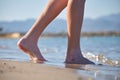 Close up of female feet walking barefoot on white grainy sand of golden beach on blue ocean water background Royalty Free Stock Photo