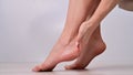 Close-up of female feet. Woman moisturizes heels with cream.