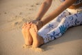 Close up of female feet. Woman sitting on the sand, practicing yoga. Paschimottanasana, Seated Forward Bend Pose. Hands holding