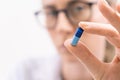 Close up of female in glasses doctor holding blue pill or capsule vitamin supplement close up Royalty Free Stock Photo