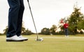 Close Up Of Female Golfer Putting Ball On Green As Man Tends Flag Royalty Free Stock Photo