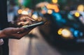 Close up female hand calling taxi with a smartphone app., businesswoman using cellphone with yellow taxi background night street