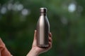 Close-up of female hand clutching reusable steel water bottle