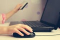 Close up of female hand on computer mouse and holding a credit card. Royalty Free Stock Photo