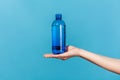 Close up female hand demonstrating plastic blue bottle with mineral water, advertising fresh pure beverage, best way to restore Royalty Free Stock Photo