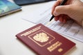 Close up of female hand filing out a visa application with a Russian passport Royalty Free Stock Photo