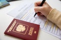 Close up of female hand filing out a visa application with a Russian passport Royalty Free Stock Photo