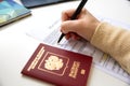 Close up of female hand filing out a visa application with a Russian passport Royalty Free Stock Photo