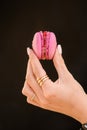 close-up of female hand gently holds delicious sweet pink macaron