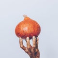 Close-up of a female hand in a gold paint holding an orange pump