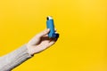 Close-up of female hand holding asthmatic inhaler on yellow background. Royalty Free Stock Photo
