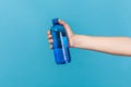 Close up female hand holding blue bottle with fresh cold mineral or sparkling water, source of energy and electrolytes